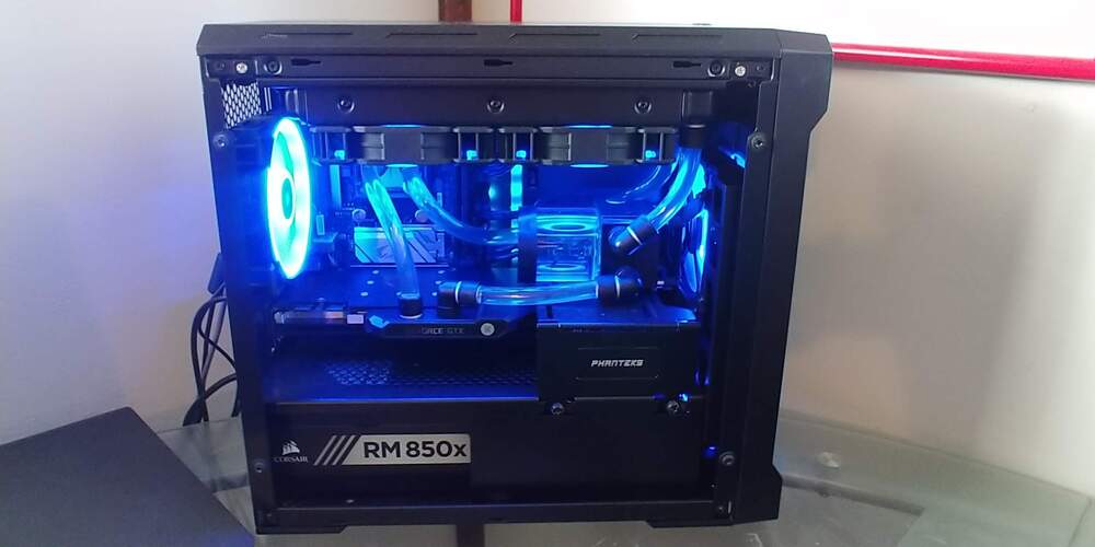 Gaming computer with blue LEDs sitting on desk.