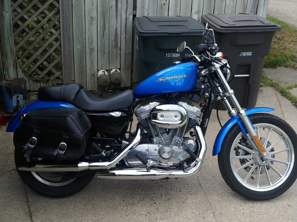 Right side of a blue 2004 Harley-Davidson Sportster 883 in front of a garage.