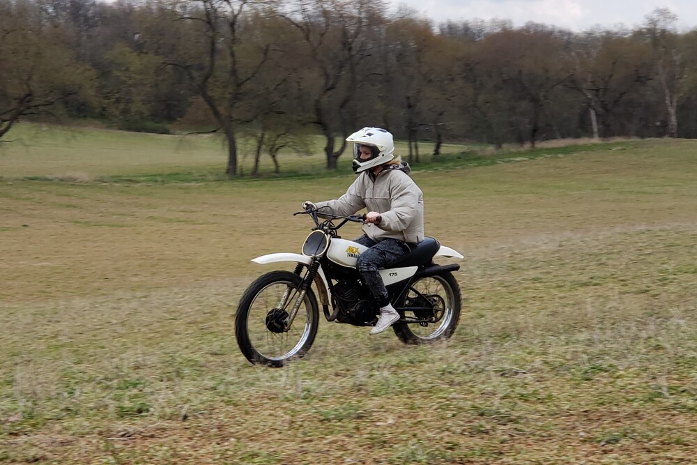 Picture of Sydney riding a dirt bike across a field.