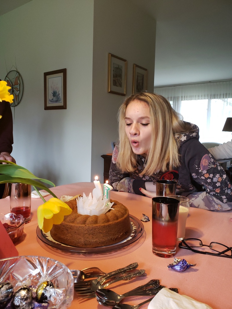 Picture of Sydney blowing out candles of a birthday bunt cake.