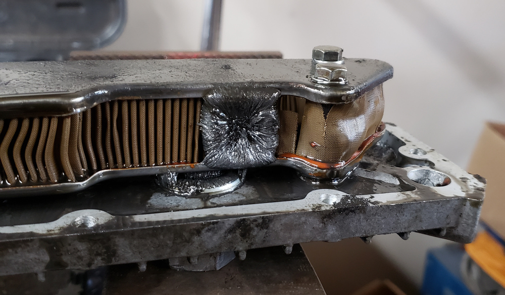 1981 XS650 oil filter with rip in its side and metal shaving buildup on magnet.